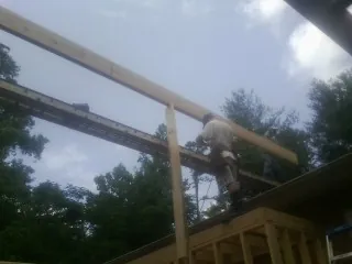 Carpenter setting a ridge beam over a new addition frame — Ice Dam Removal by Roofing Brothers in Wading River