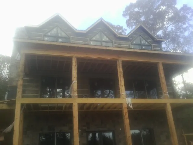 Dormers and porch framing on a large log home under construction — Roof Coating work by our crew in Wading River