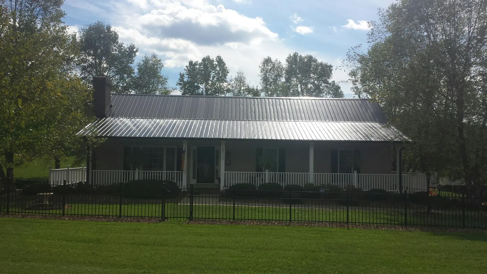 Gray metal roof on a brick ranch with a full width front porch — Gutter Guard Installation work by our crew in Wading River