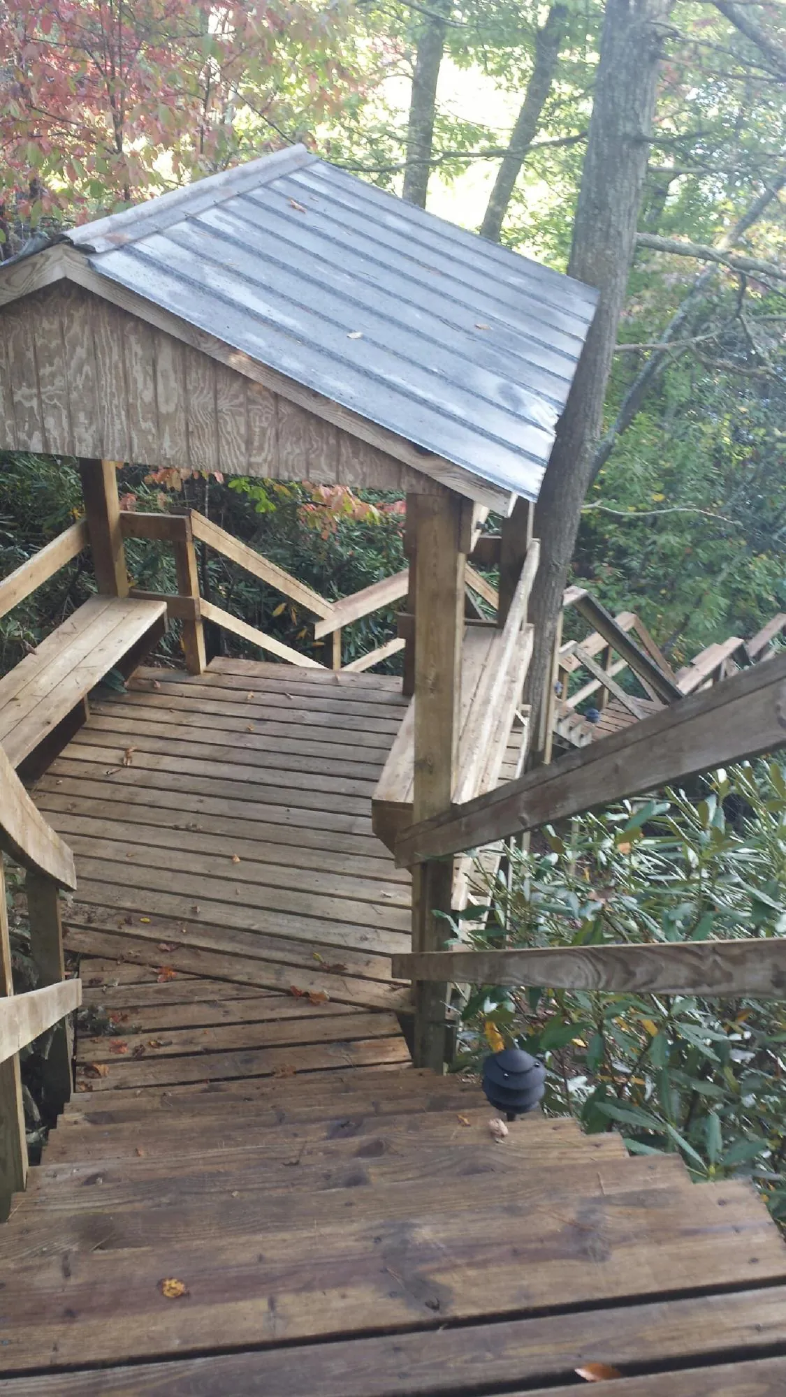 Metal roofed shelter over wooden steps on a wooded walkway — Skylight Repair & Installation work by our crew in Wading River