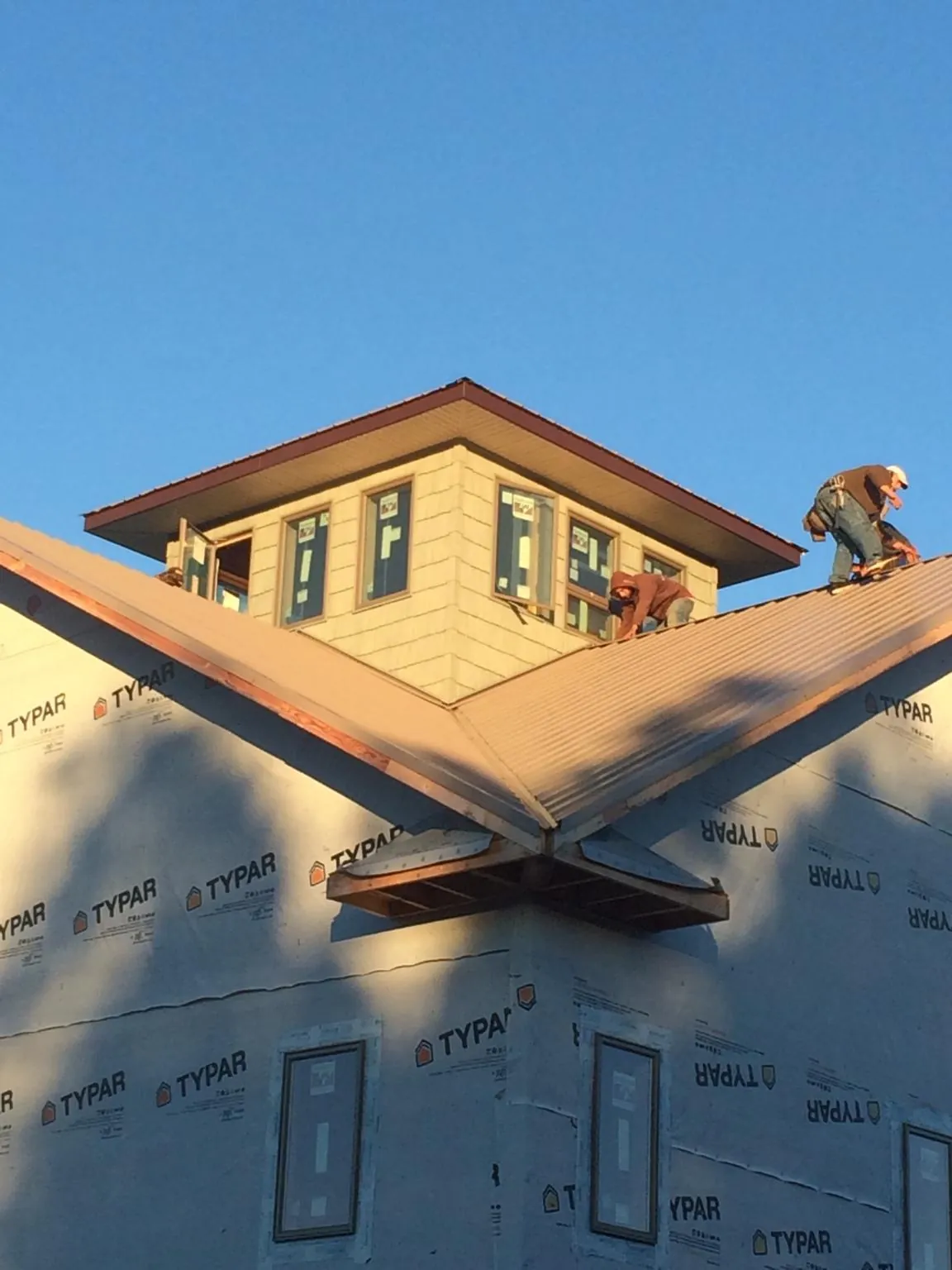 Roofers working around a rooftop cupola on a new metal roof at sunset — Roof Waterproofing in Wading River by Roofing Brothers